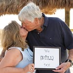 Older couple holding a sign saying we still do