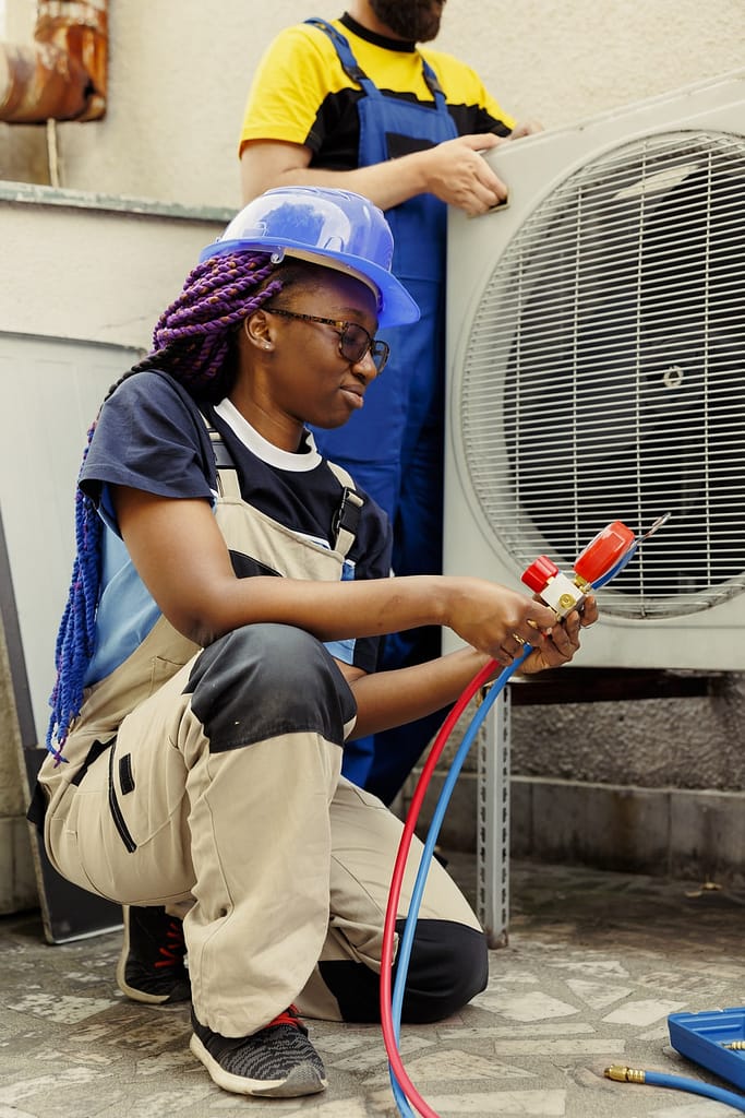 A technician with purple braids performs essential HVAC maintenance on an outdoor unit in Sarasota County.